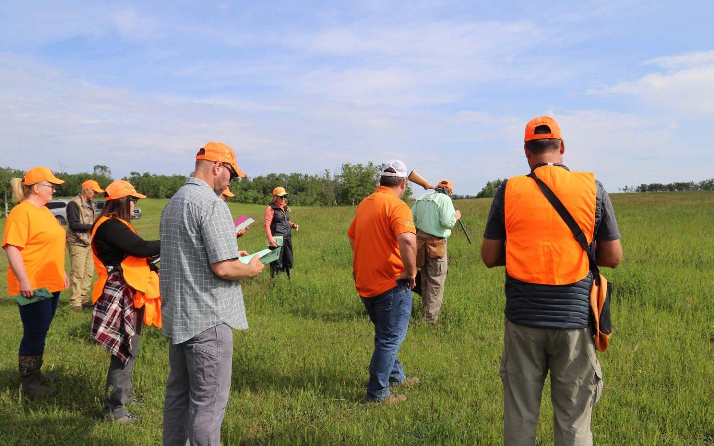 a group of people in bright orange clothing standing in a green open field