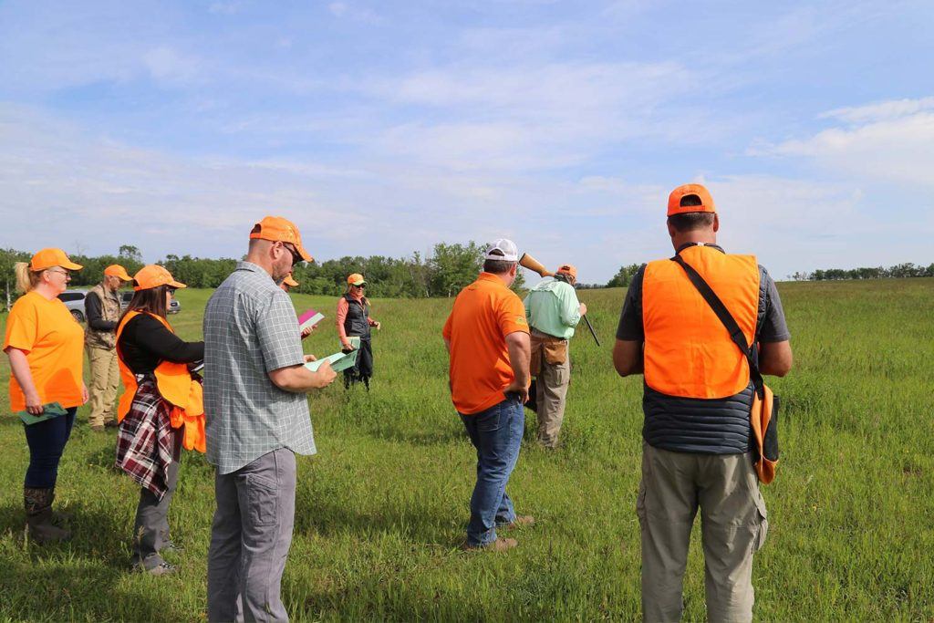 a group of people in bright orange clothing standing in a green open field