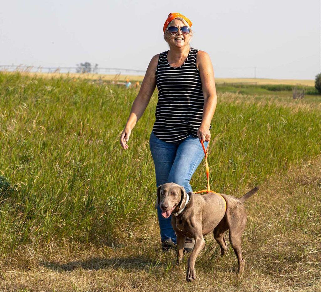 a woman walking a dog on a leash in a field