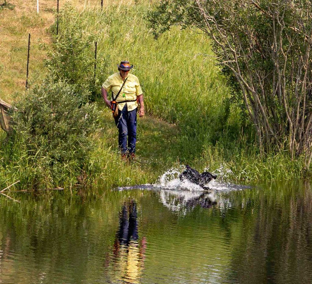 a man standing next to a lake with a dog