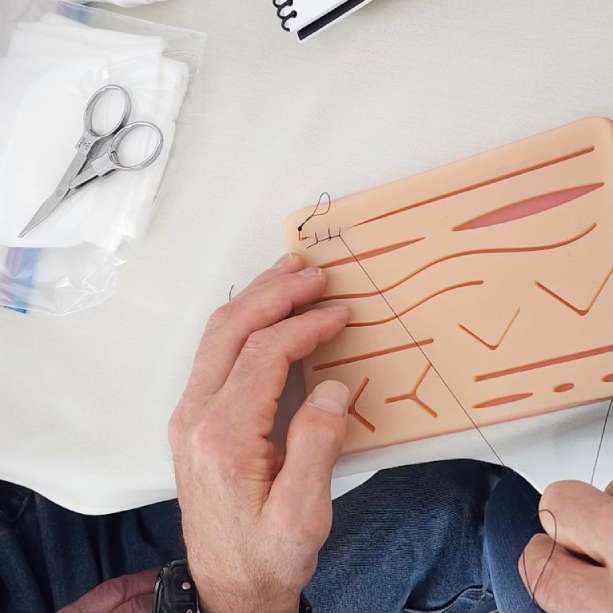 person sewing up a simulated wound