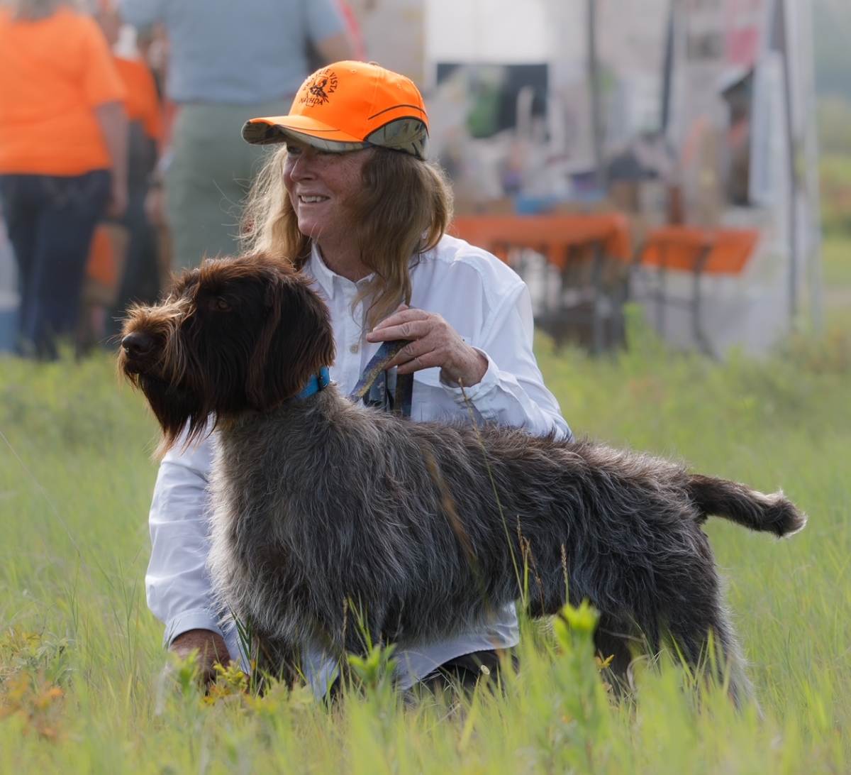 Dog standing on green field with her owner